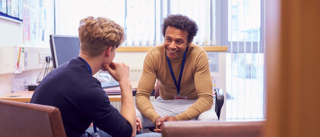 Male College Student Meeting With Campus Counselor Discussing Mental Health Issues at Northern College