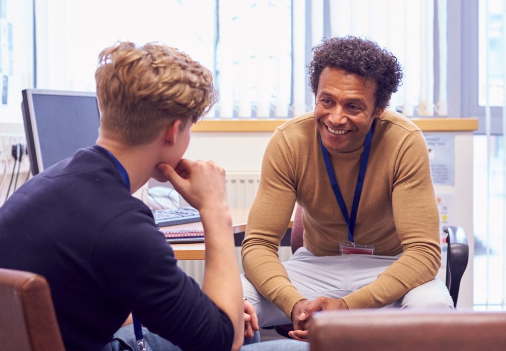 Male College Student Meeting With Campus Counselor Discussing Mental Health Issues at Northern College