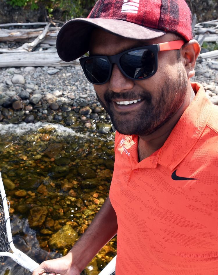 Northern College Student Recruiter, Sumit Swami, outside with fishing net at river