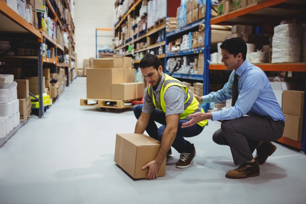 Worker and supervisor lifting box in warehouse