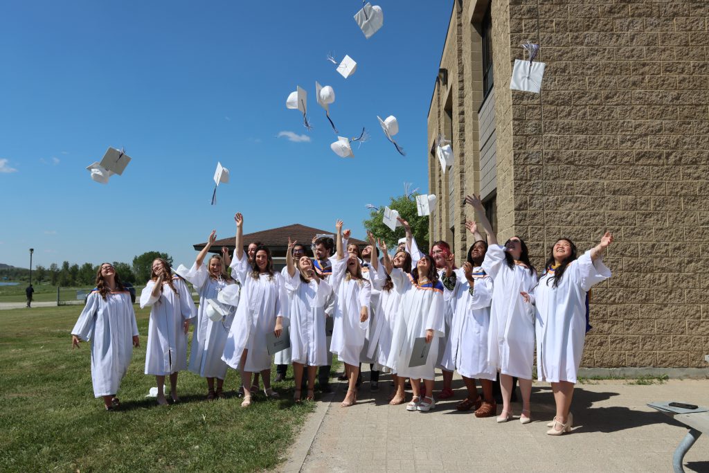 Northern College Grads throwing their hats in the air outside