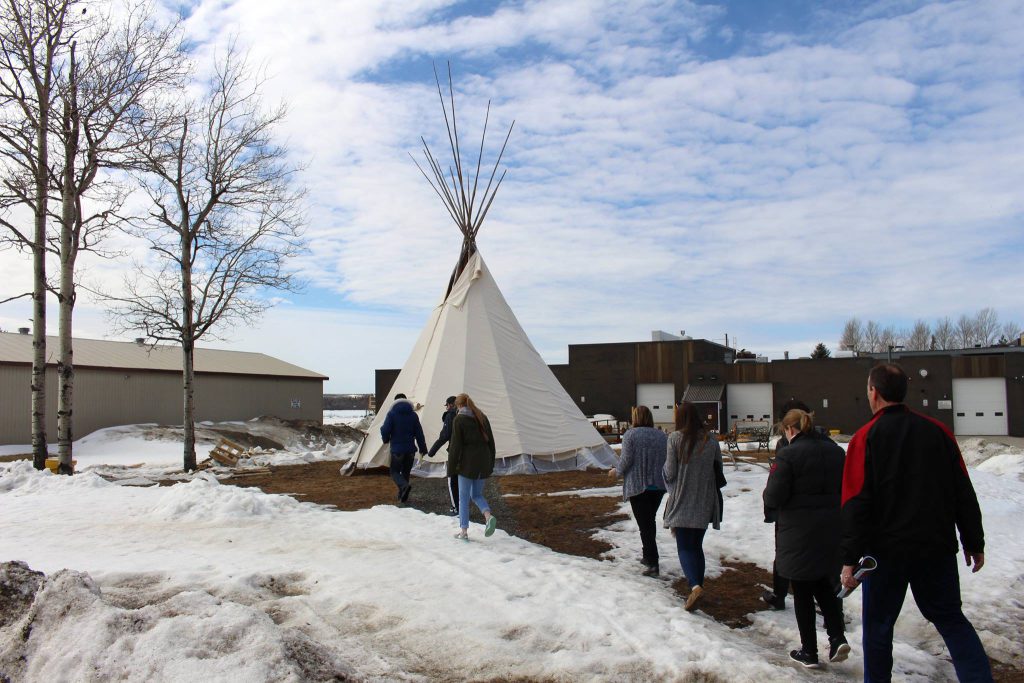 Students touring campus outside near tipi