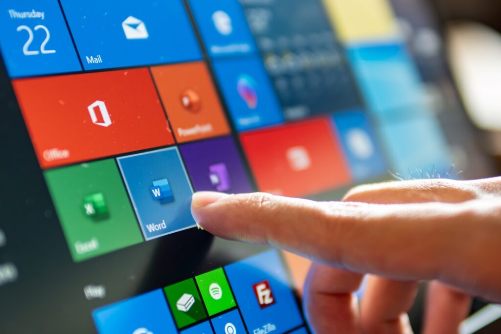 person tapping on microsoft office suite program on computer screen
