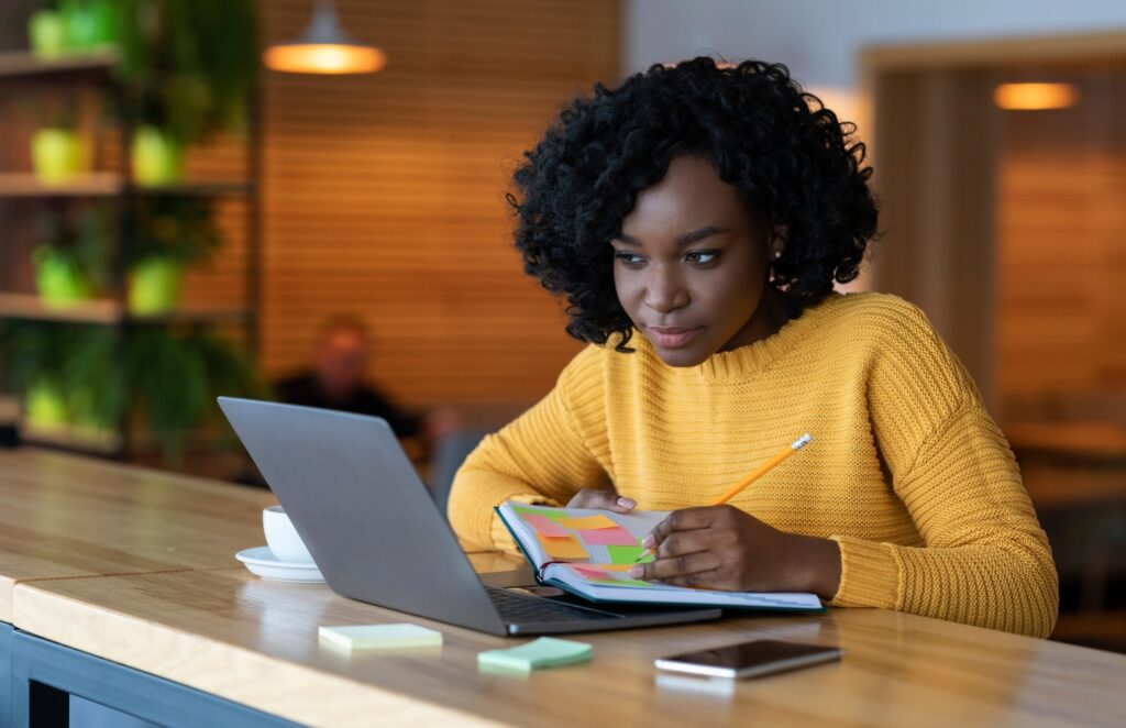 office worker taking notes at desk with computer